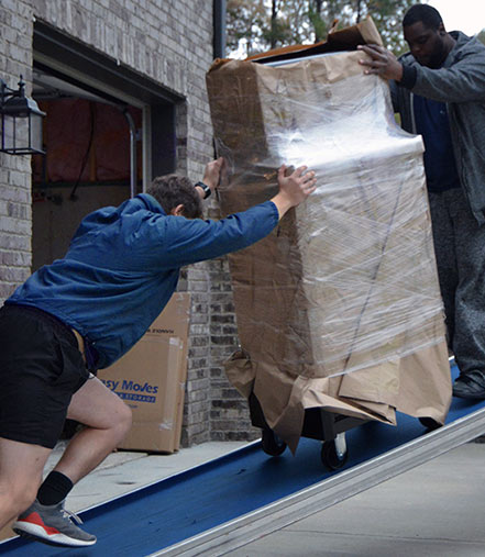 Movers moving tool chest up ramp.